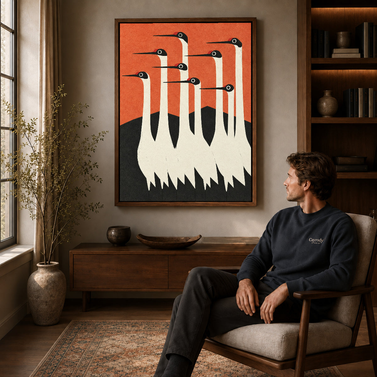 Crane canvas wall art in a walnut frame above a console beside a seated man.