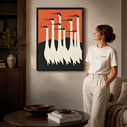 Crane canvas wall art shown in the black frame option with warm furnishings and a standing woman.