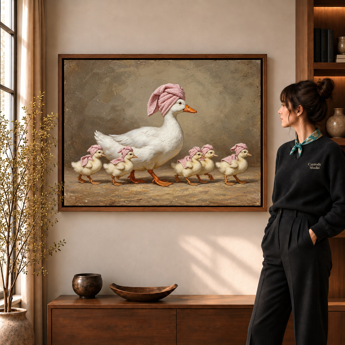 vintage spa duck family canvas art in a walnut frame beside a standing woman and wooden console.
