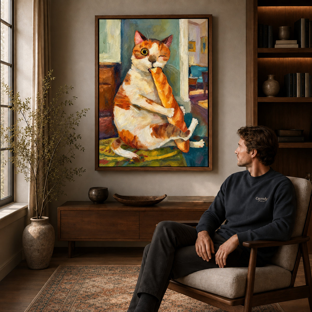 painterly baguette cat canvas art in a walnut frame above a console beside a seated man.