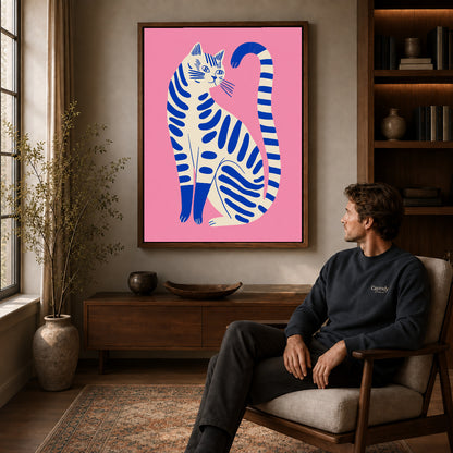 Striped cat canvas art in a walnut frame above a console beside a seated man.