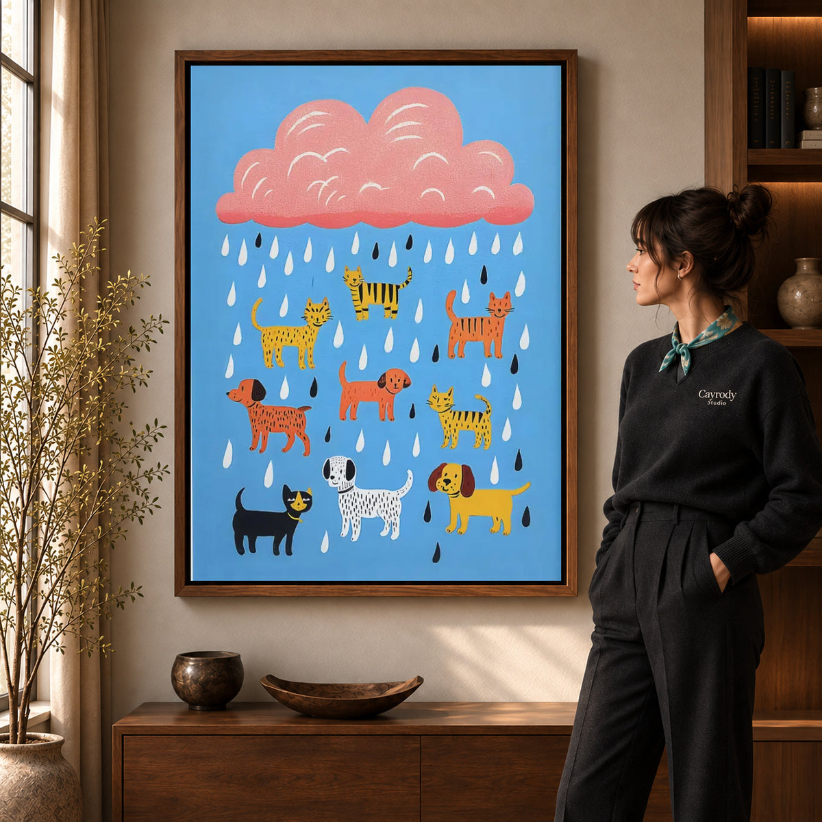 Raining pets canvas art in a walnut frame beside a standing woman and wooden console.