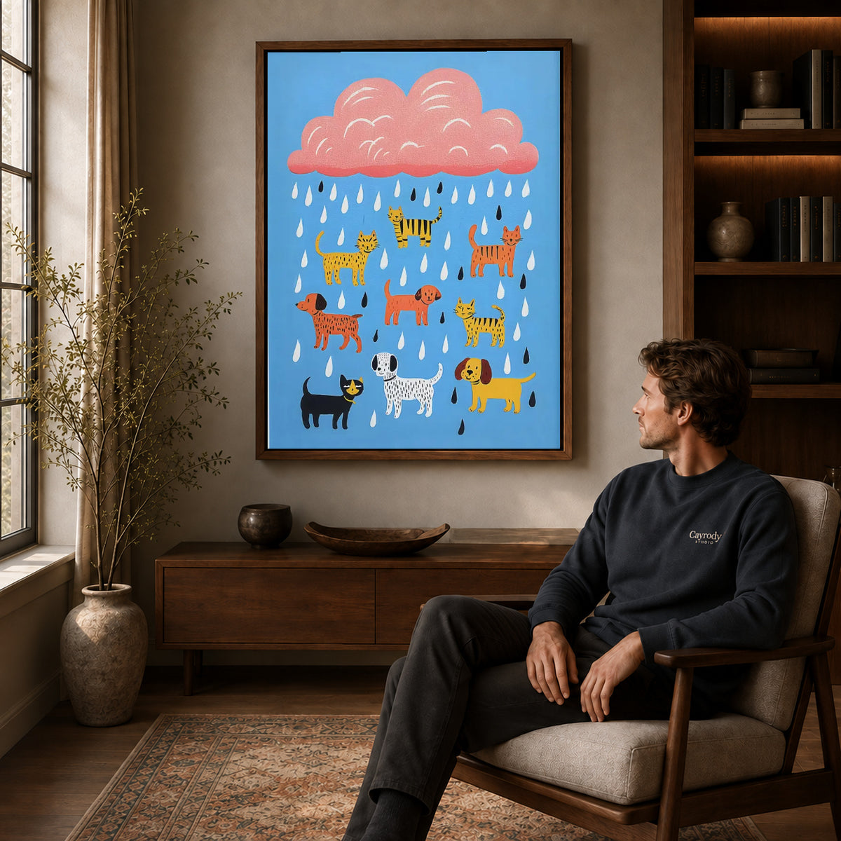 Raining pets canvas art in a walnut frame above a console beside a seated man.