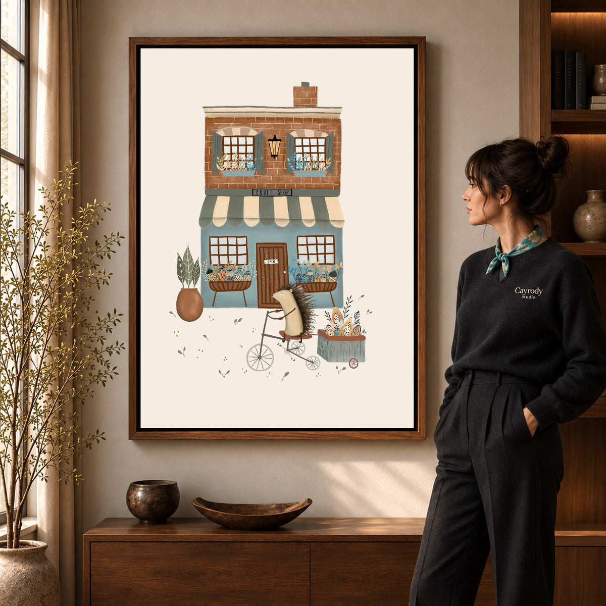 Hedgehog fruit shop canvas art in a walnut frame beside a standing woman and wooden console.