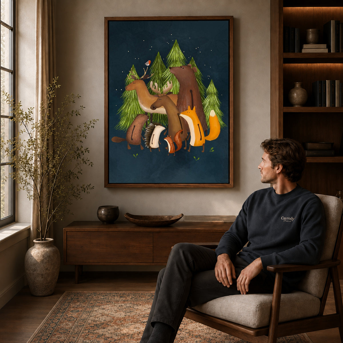 Woodland friends canvas art in a walnut frame above a console beside a seated man.