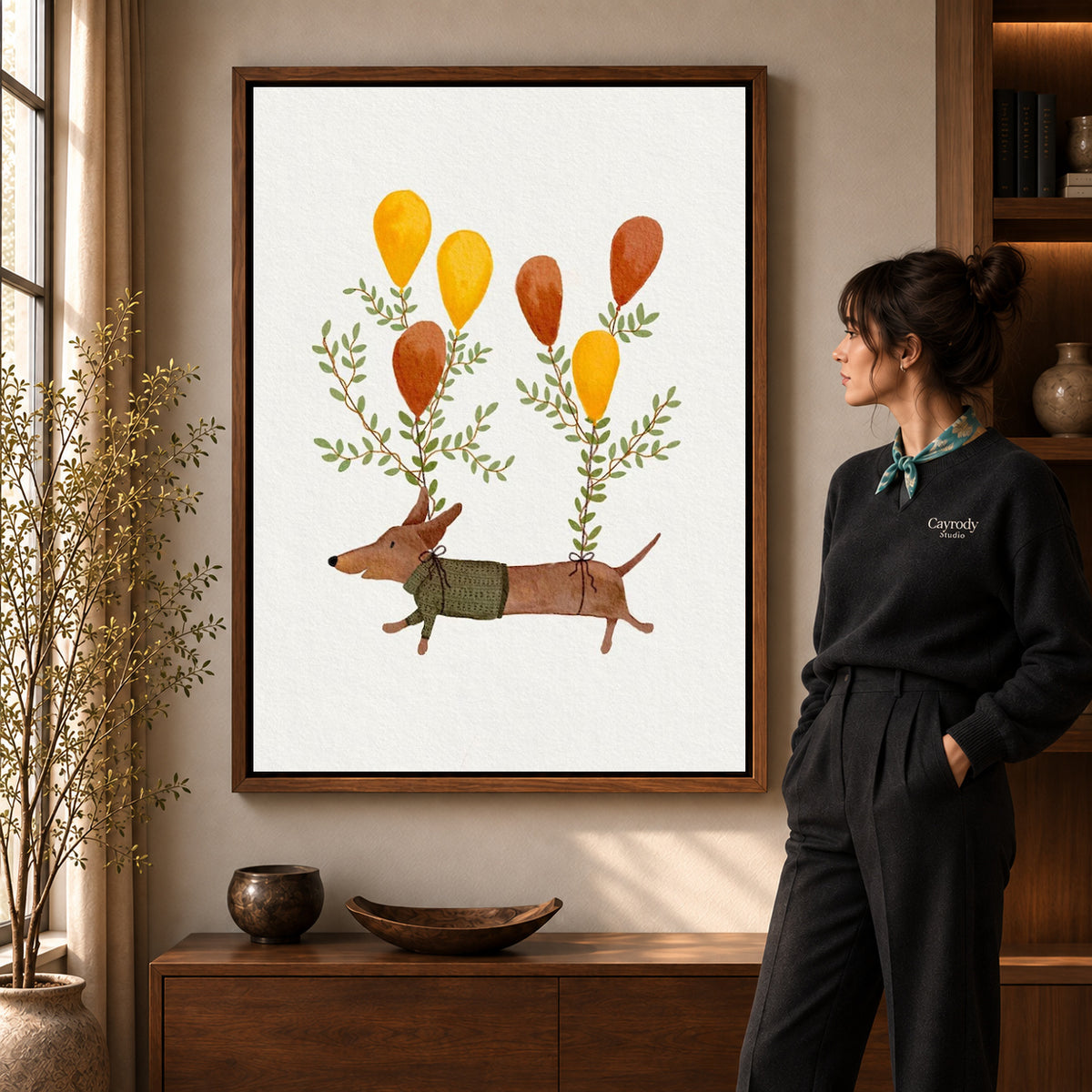 Balloon dachshund canvas art in a walnut frame beside a standing woman and wooden console.