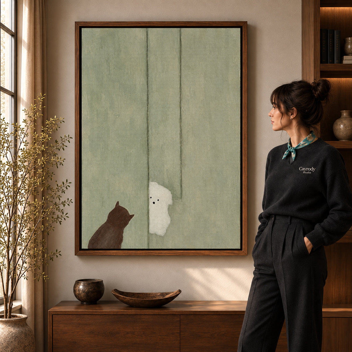 Ghost cat canvas art in a walnut frame beside a standing woman and wooden console.