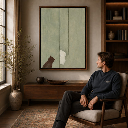 Ghost cat canvas art in a walnut frame above a console beside a seated man.