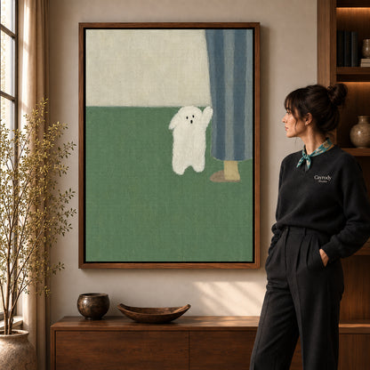 Little ghost canvas art in a walnut frame beside a standing woman and wooden console.