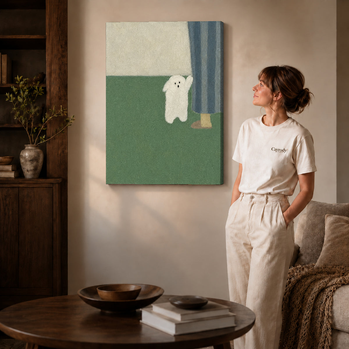 Little ghost canvas art on gallery-wrapped canvas with visible depth beside a woman in a warm living room.