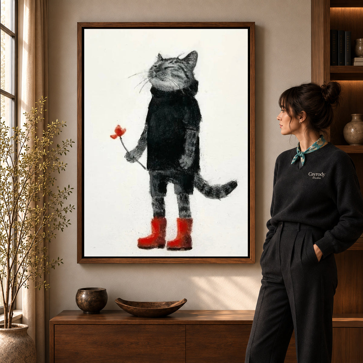 Cat red boots canvas art in a walnut frame beside a standing woman and wooden console.