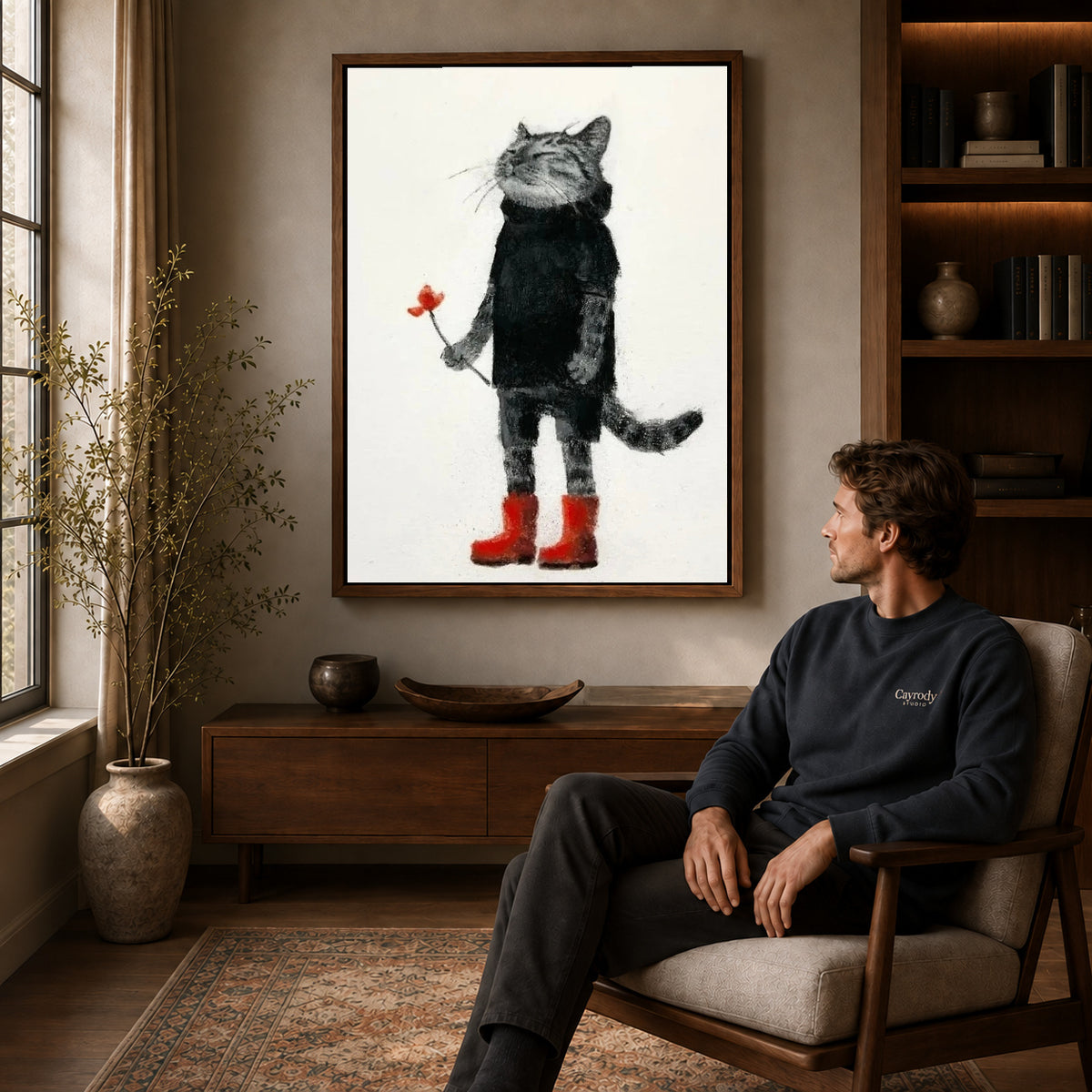 Cat red boots canvas art in a walnut frame above a console beside a seated man.