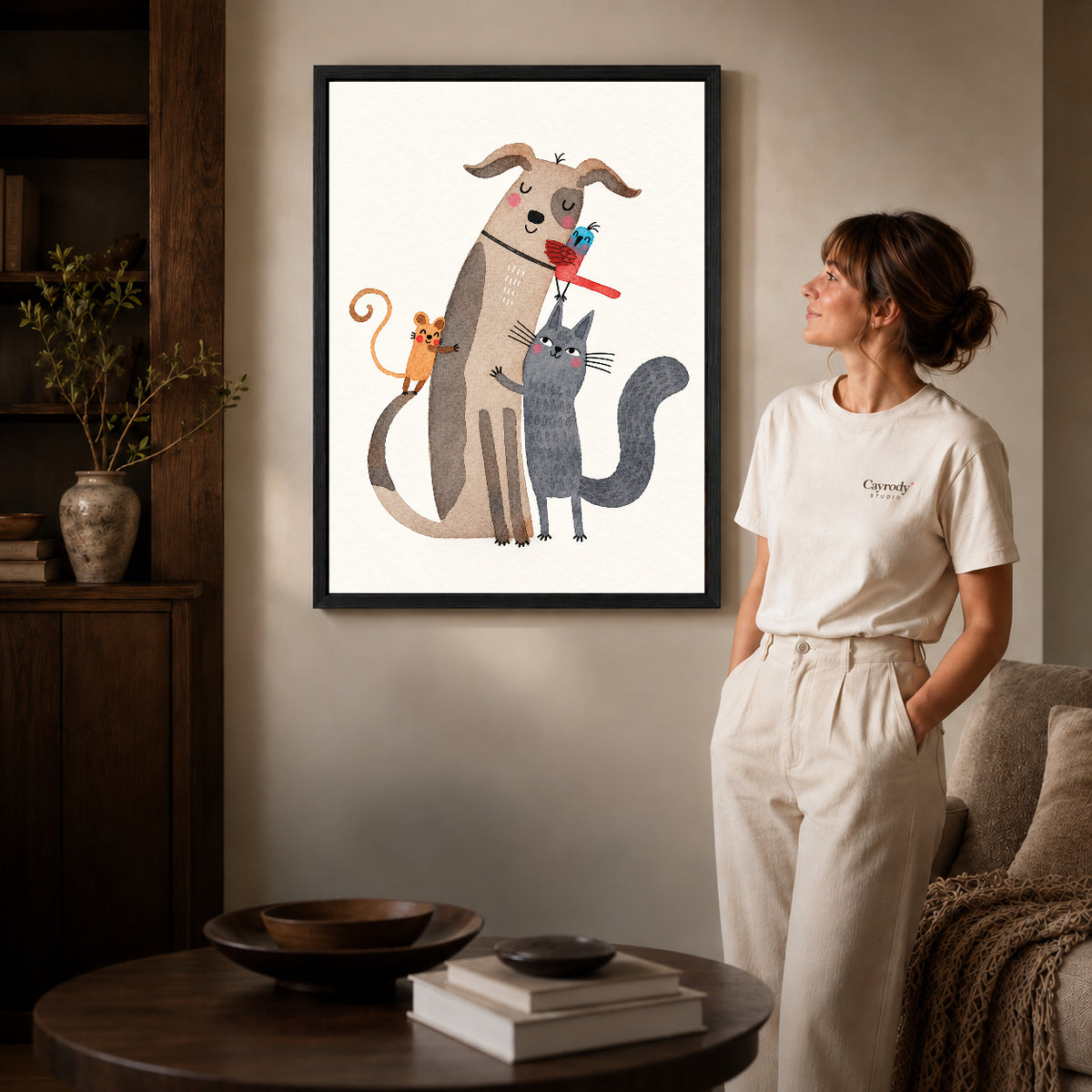 Animal friends canvas art in a black frame beside a woman and round wooden table.