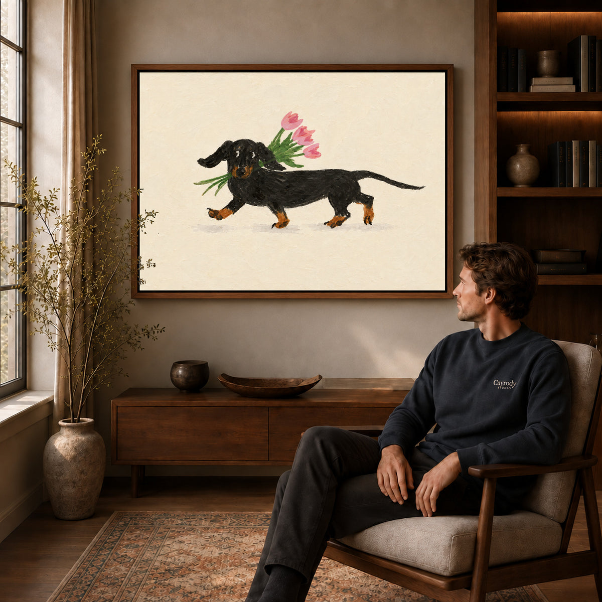 Dachshund tulips canvas art in a walnut frame above a console beside a seated man.