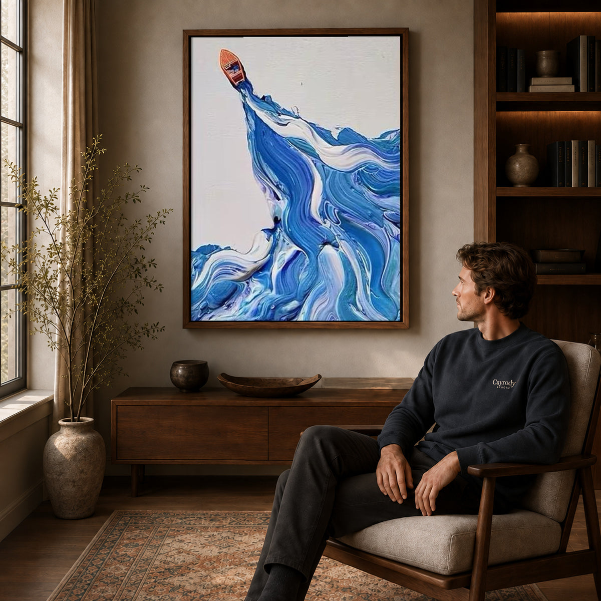Blue wave canvas art in a walnut frame above a console beside a seated man.