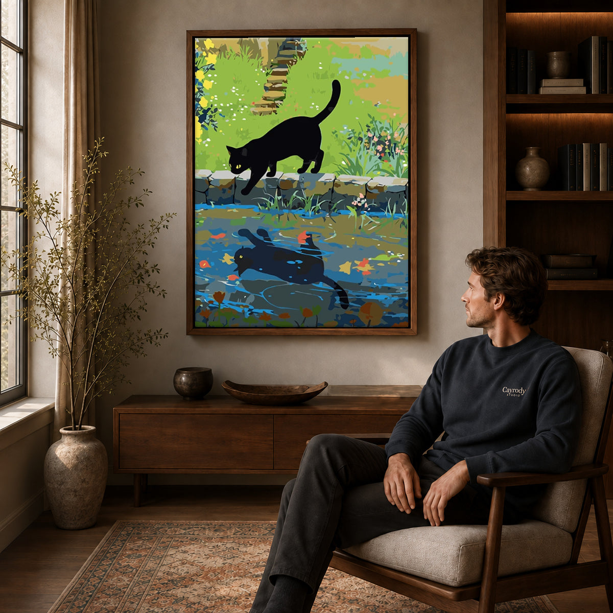 Black cat canvas art in a walnut frame above a console beside a seated man.