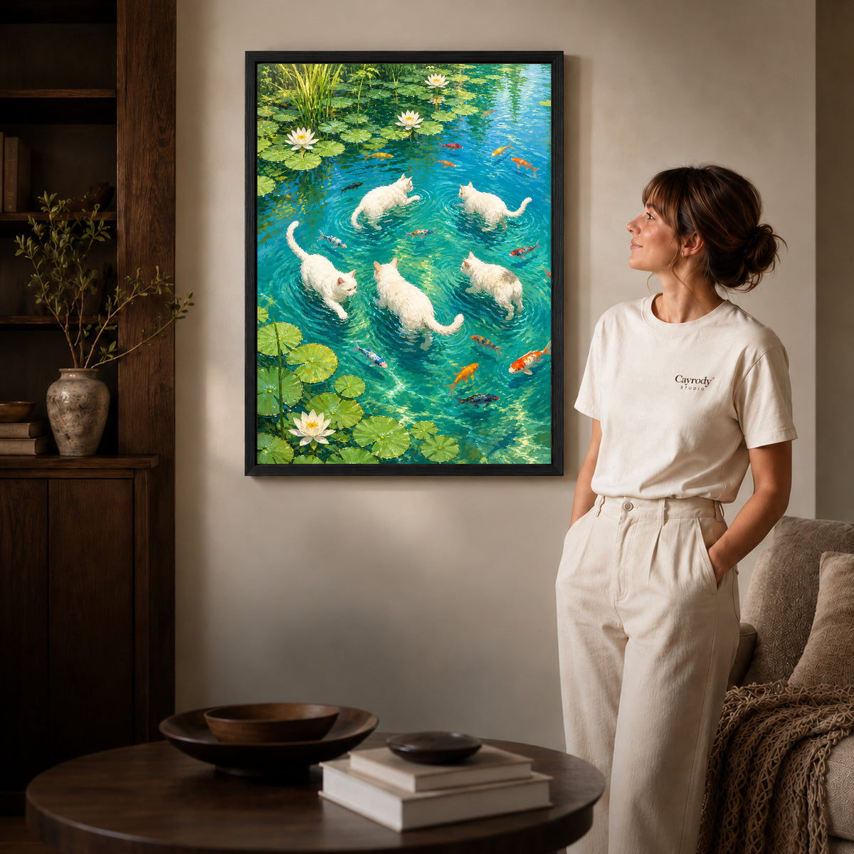 Cats lily pond canvas art in a black frame beside a woman and round wooden table.