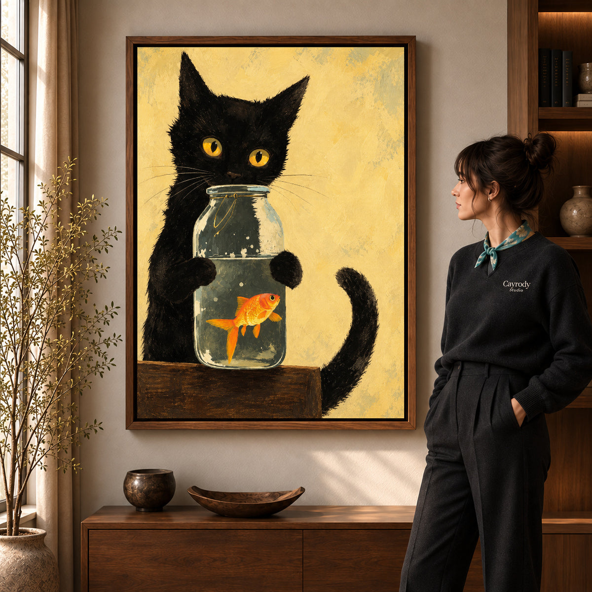 Black cat goldfish canvas art in a walnut frame beside a standing woman and wooden console.