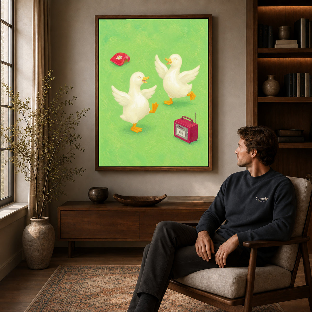 Dancing ducks canvas art in a walnut frame above a console beside a seated man.