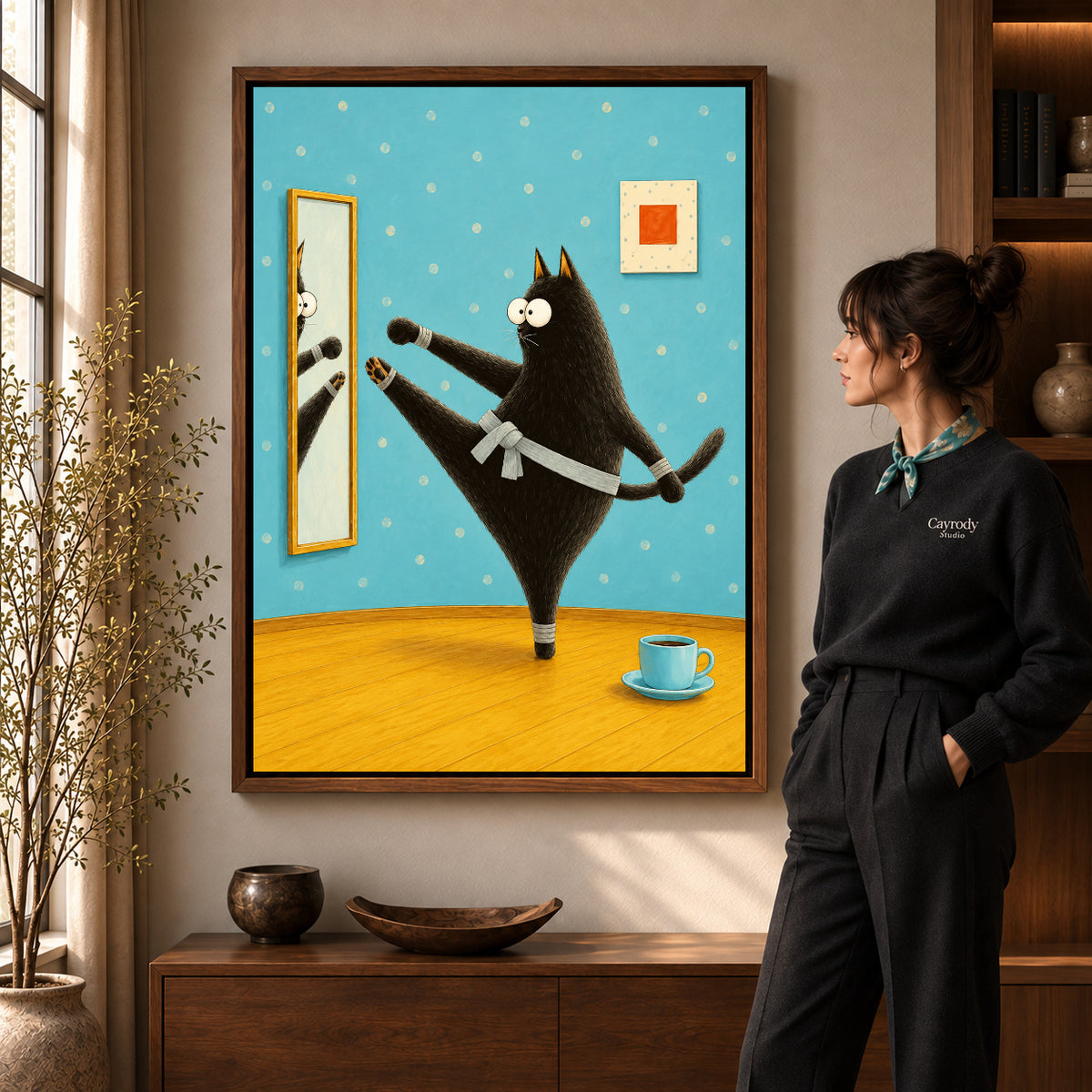 whimsical karate cat canvas art in a walnut frame beside a standing woman and wooden console.