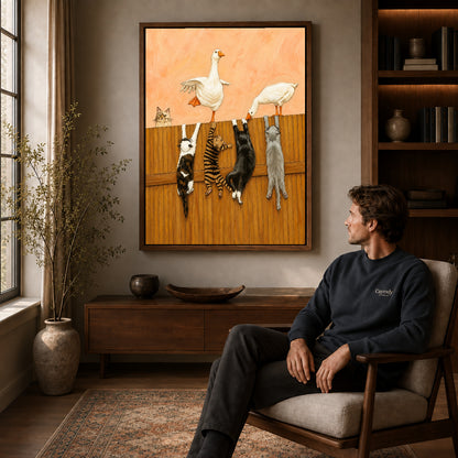 Geese and cats canvas art in a walnut frame above a console beside a seated man.