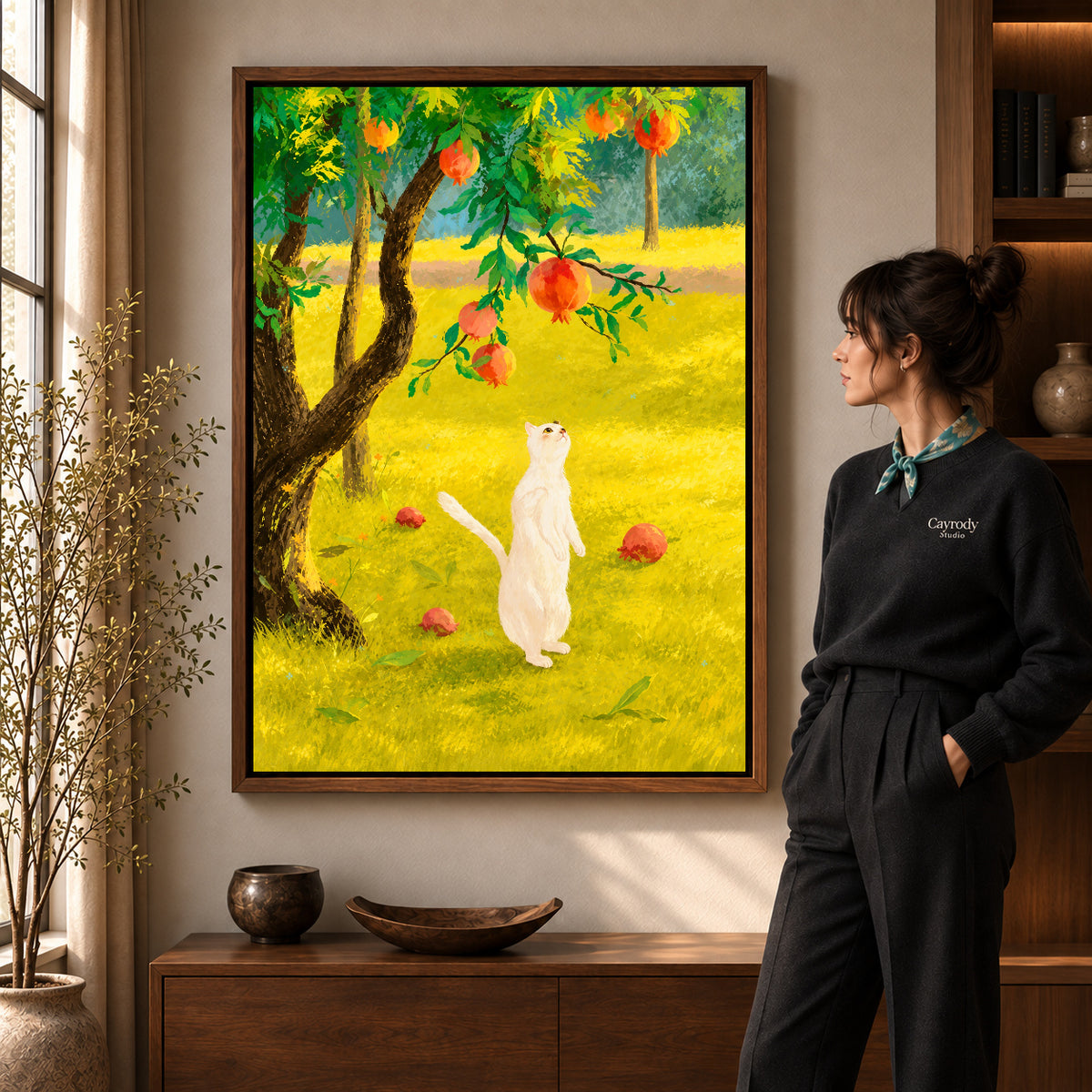 Orchard cat canvas art in a walnut frame beside a standing woman and wooden console.