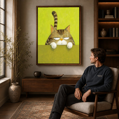 Grumpy tabby canvas art in a walnut frame above a console beside a seated man.