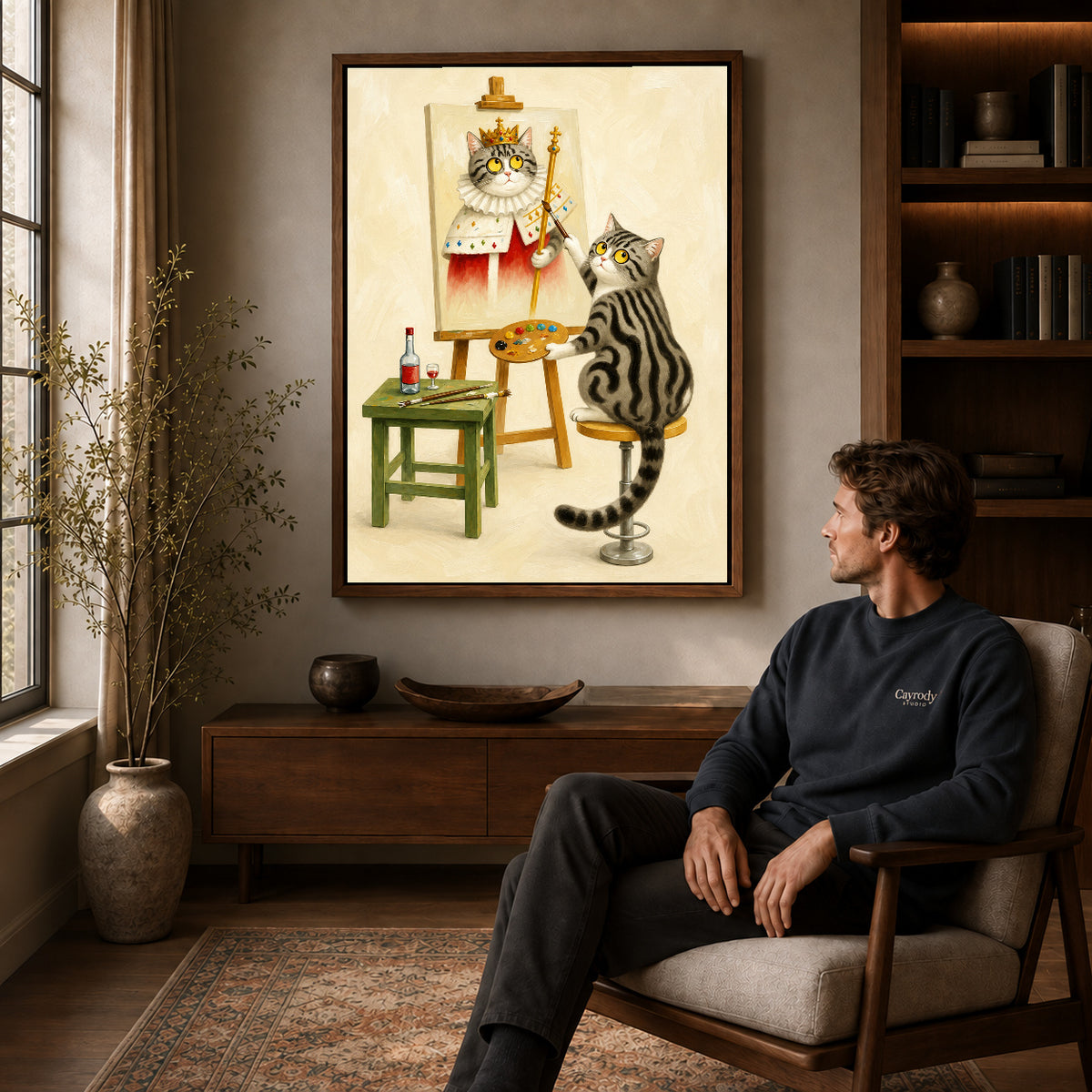 Cat artist canvas art in a walnut frame above a console beside a seated man.