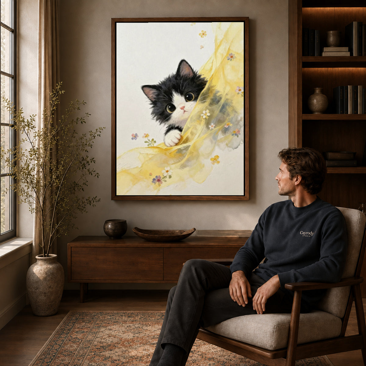 Curious kitten canvas art in a walnut frame above a console beside a seated man.