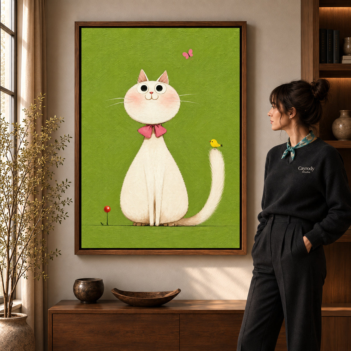 White cat canvas art in a walnut frame beside a standing woman and wooden console.