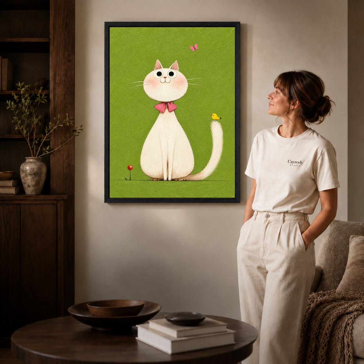White cat canvas art shown in the black frame option with warm furnishings and a standing woman.