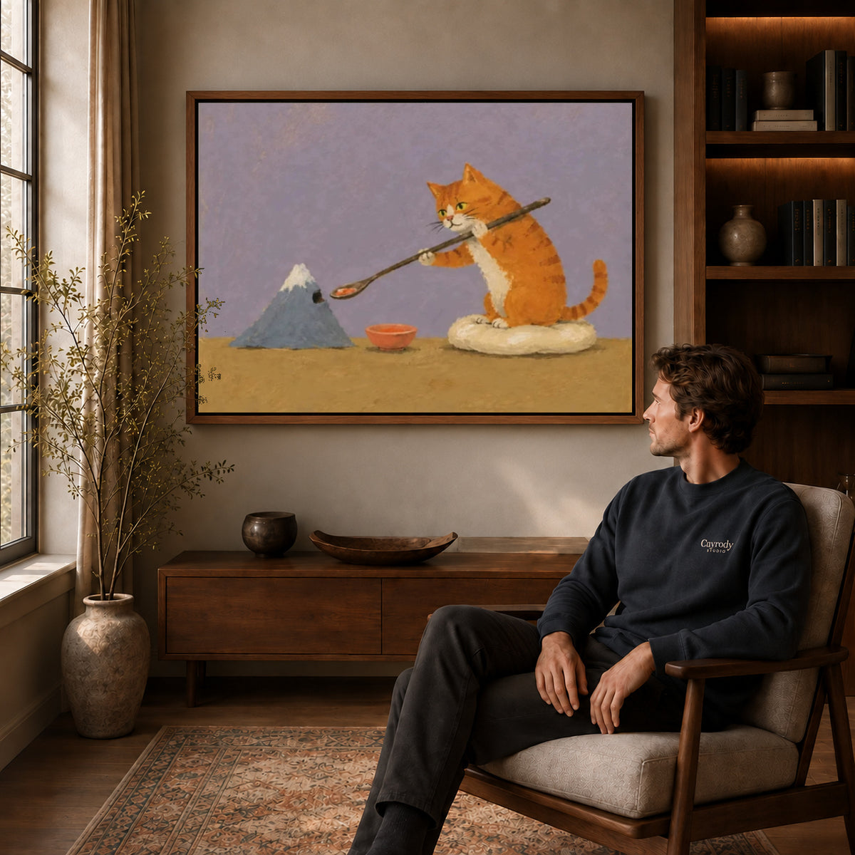 Painter cat canvas art in a walnut frame above a console beside a seated man.
