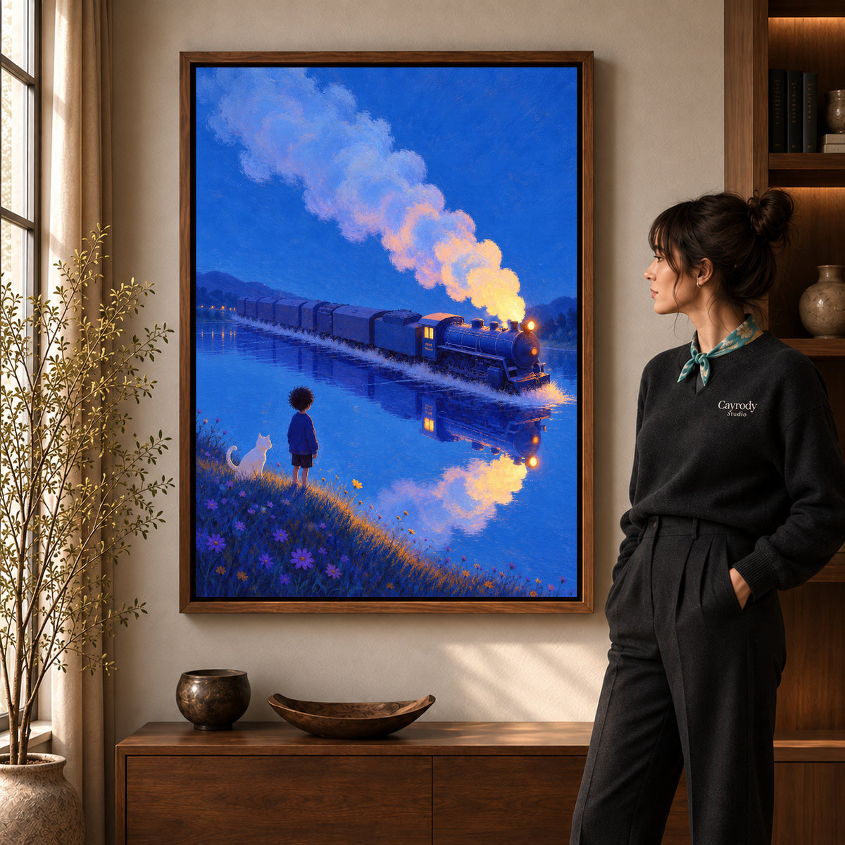 Train lake canvas art in a walnut frame beside a standing woman and wooden console.