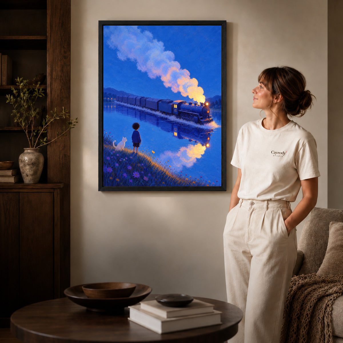 Train lake canvas art in a black frame above a round table beside a standing woman.