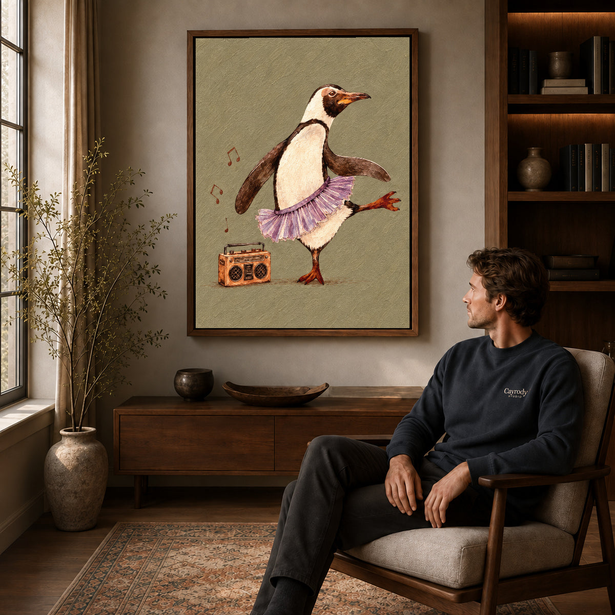 Dancing penguin canvas art in a walnut frame above a console beside a seated man.