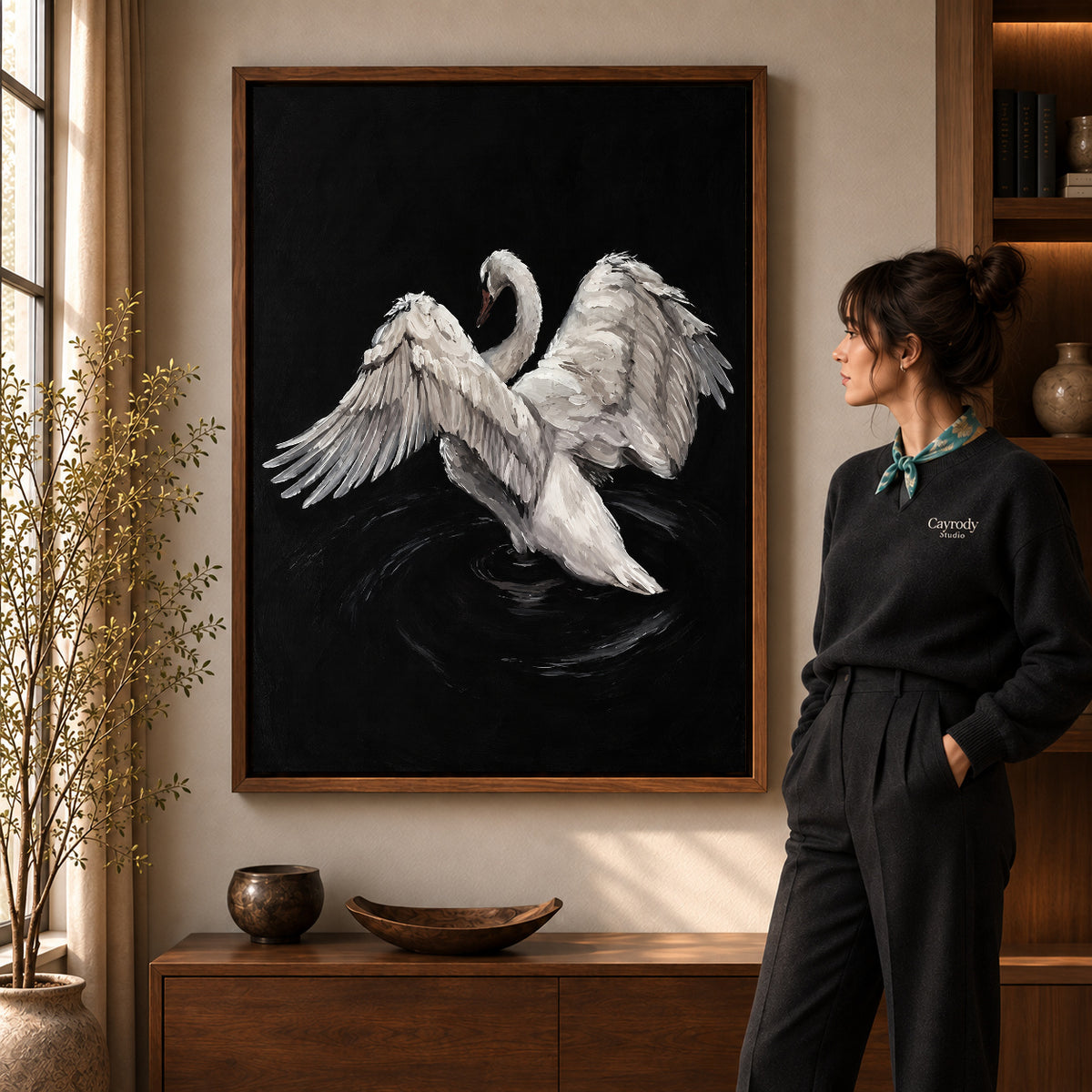 White swan canvas art in a walnut frame beside a standing woman and wooden console.