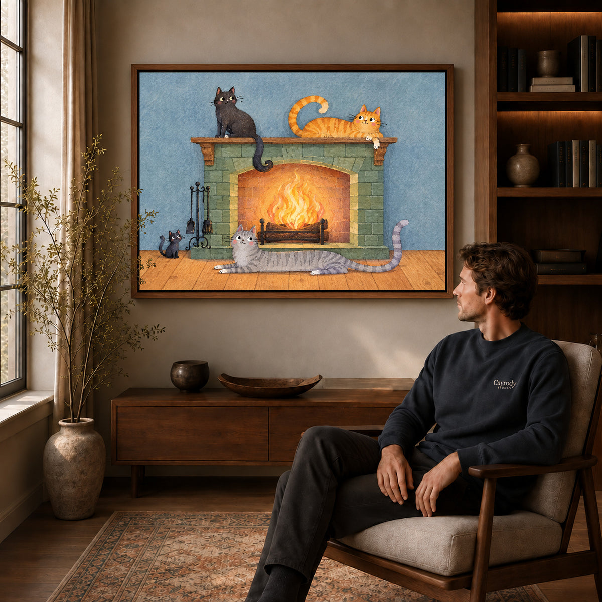 Fireplace cats canvas art in a walnut frame above a console beside a seated man.
