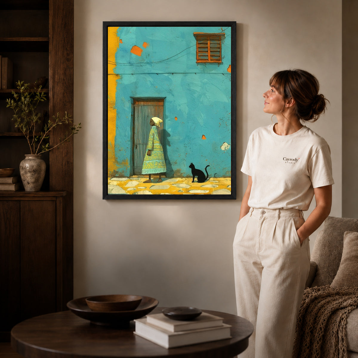 Turquoise street canvas art shown in the black frame option with warm furnishings and a standing woman.