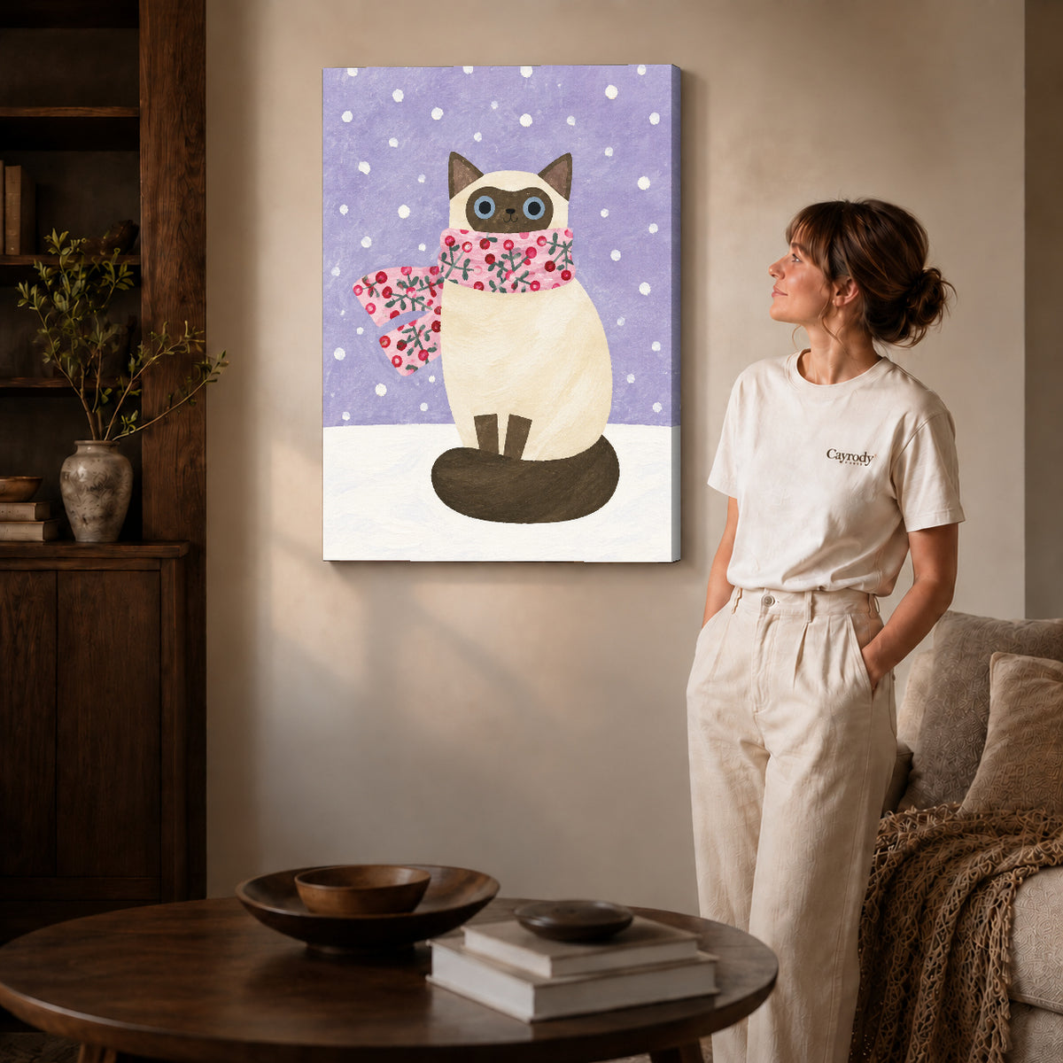 Winter cat canvas art on gallery-wrapped canvas with natural edge shading beside a standing woman.