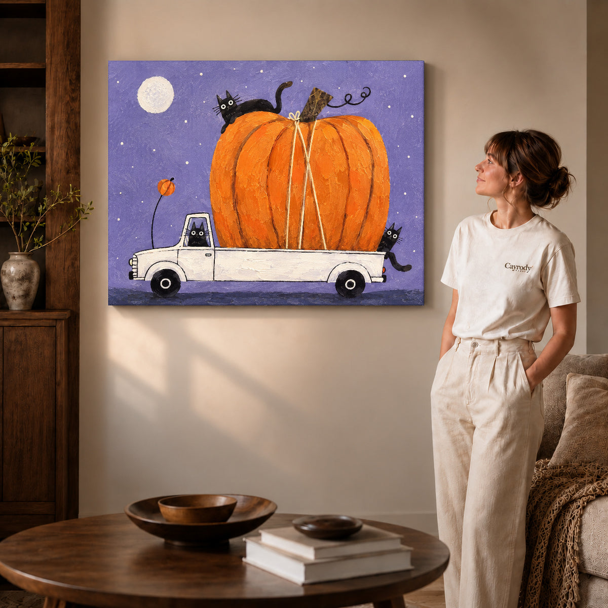 Pumpkin truck cats canvas art on gallery-wrapped canvas with visible depth beside a woman in a warm living room.