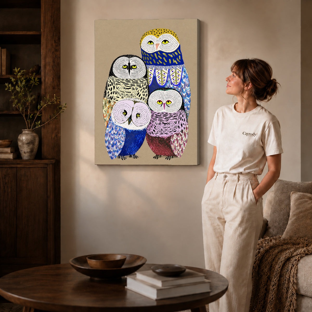 Owl family canvas art on gallery-wrapped canvas with natural edge shading beside a standing woman.
