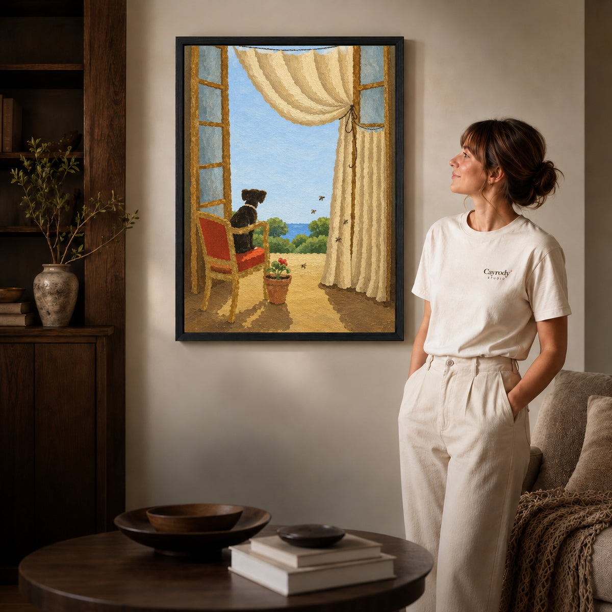Window dog canvas art in a black frame beside a woman and round wooden table.