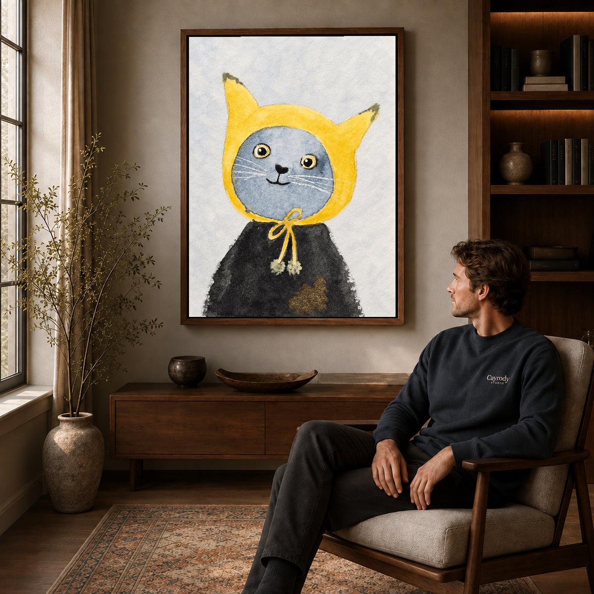 yellow hood cat canvas art in a walnut frame above a console beside a seated man.