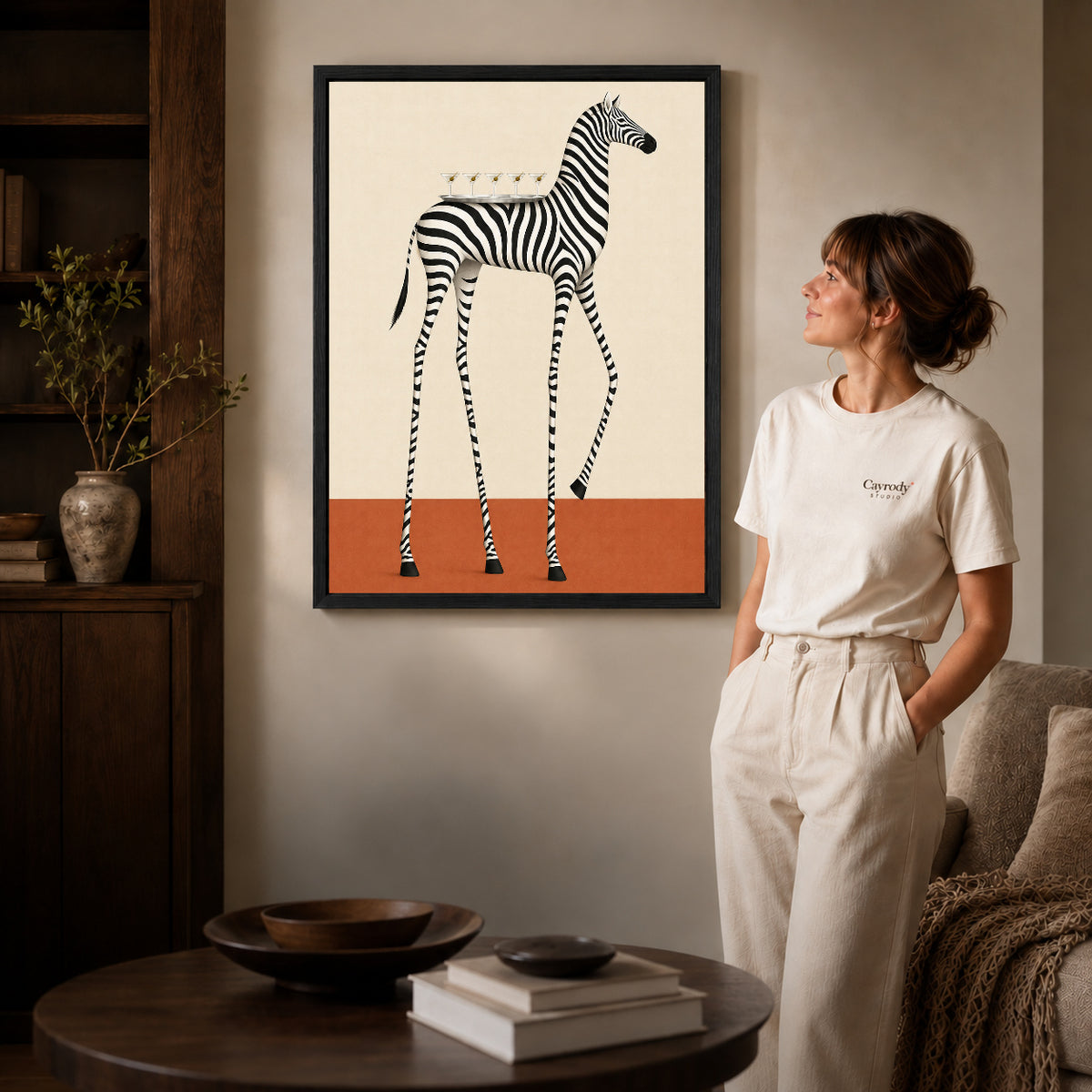 martini tray zebra canvas art in a black frame beside a woman and round wooden table.