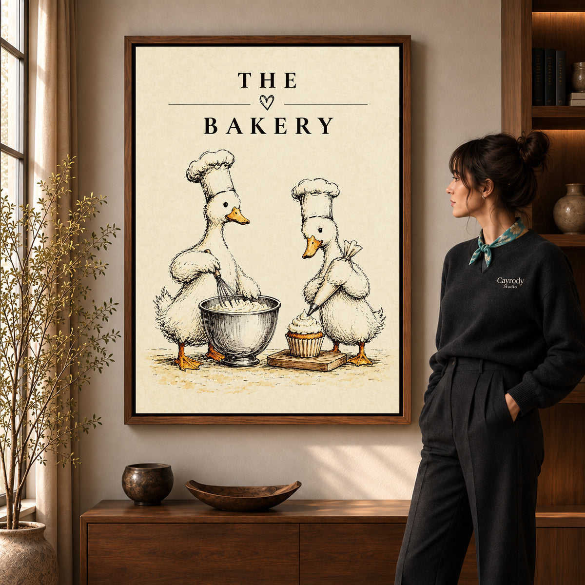 vintage bakery ducks canvas art in a walnut frame beside a standing woman and wooden console.