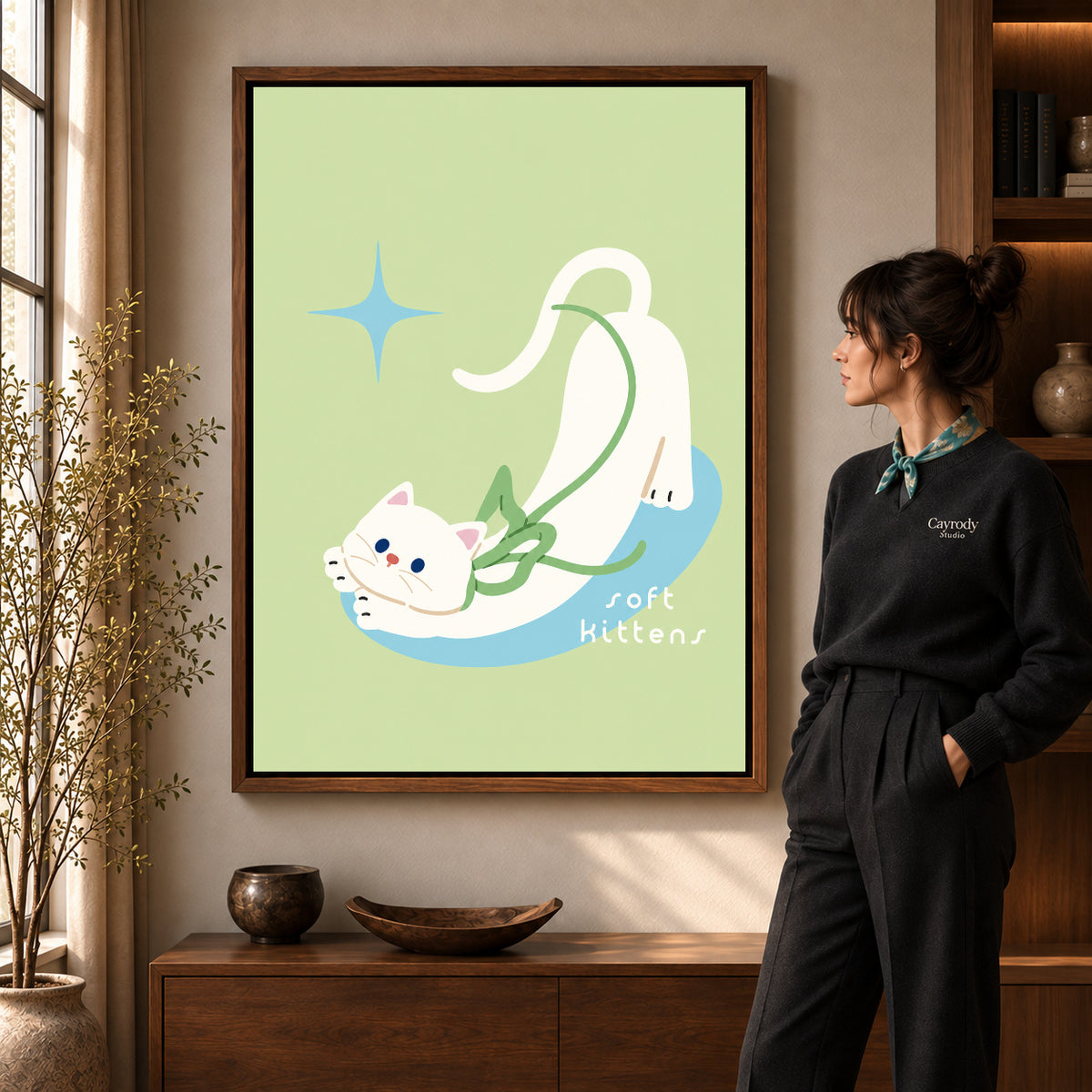 stretching white kitten canvas art in a walnut frame beside a standing woman and wooden console.