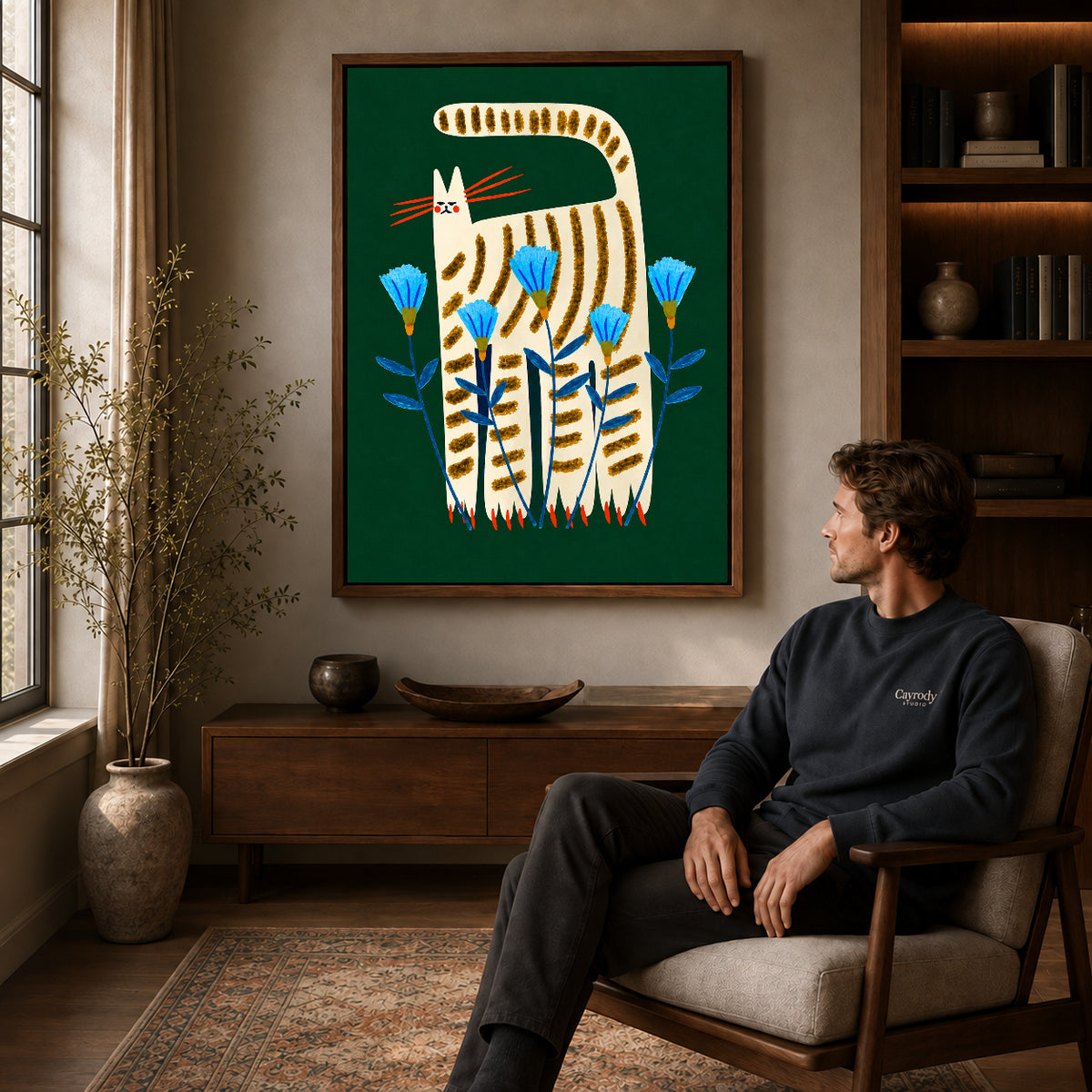 striped floral cat canvas art in a walnut frame above a console beside a seated man.