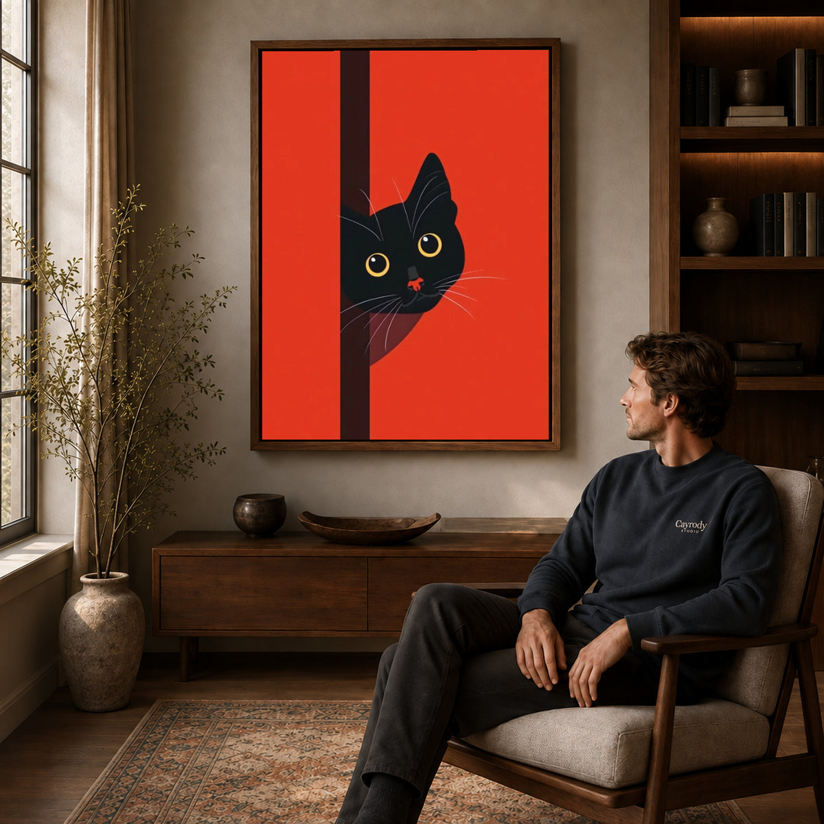 peeking black cat canvas art in a walnut frame above a console beside a seated man.