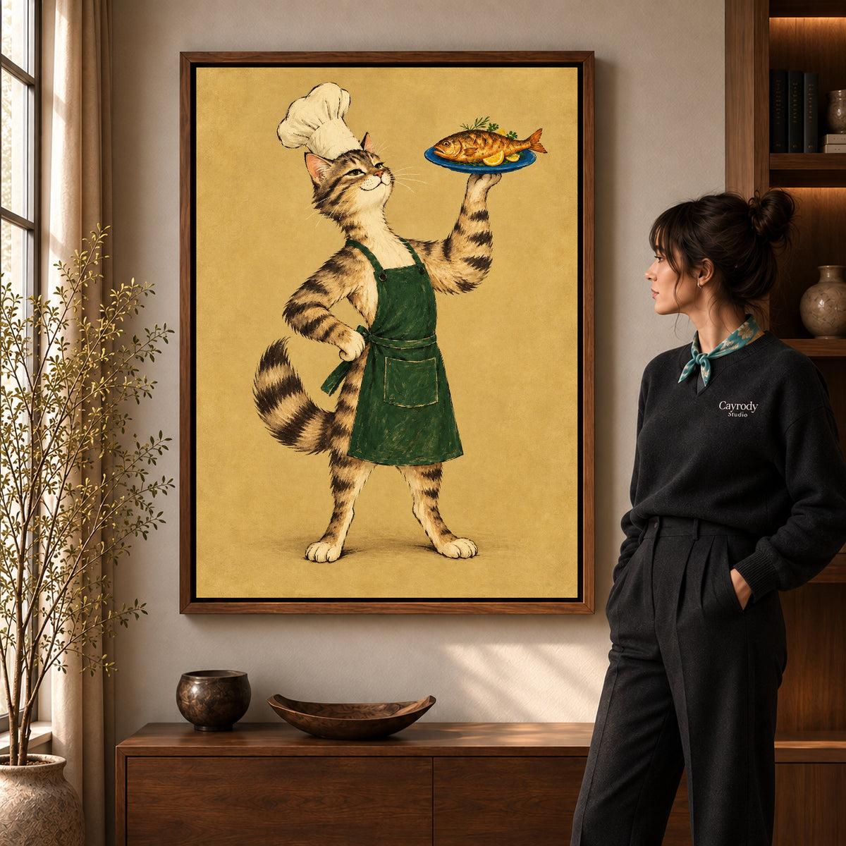 vintage fish chef cat canvas art in a walnut frame beside a standing woman and wooden console.