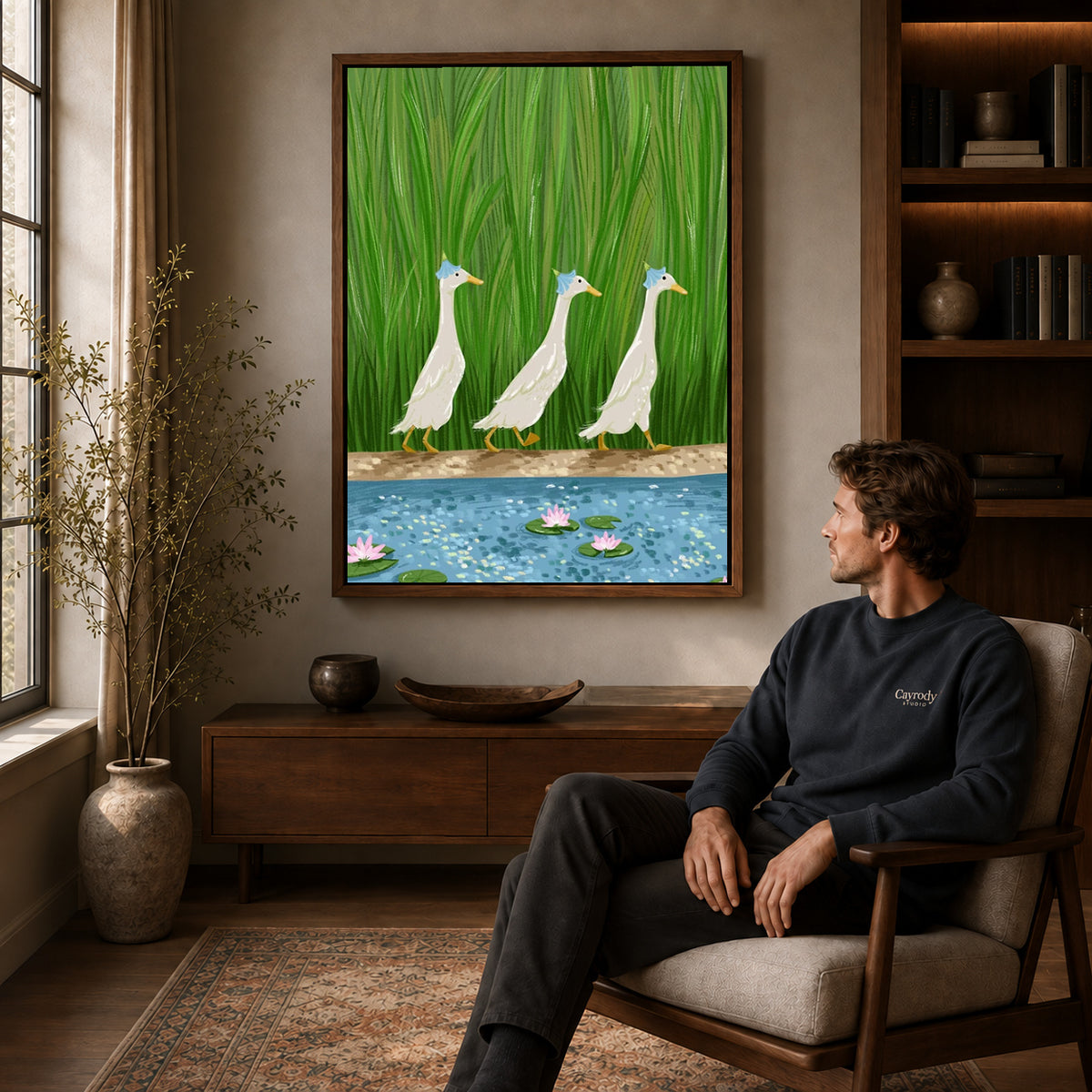 folk pond geese canvas art in a walnut frame above a console beside a seated man.